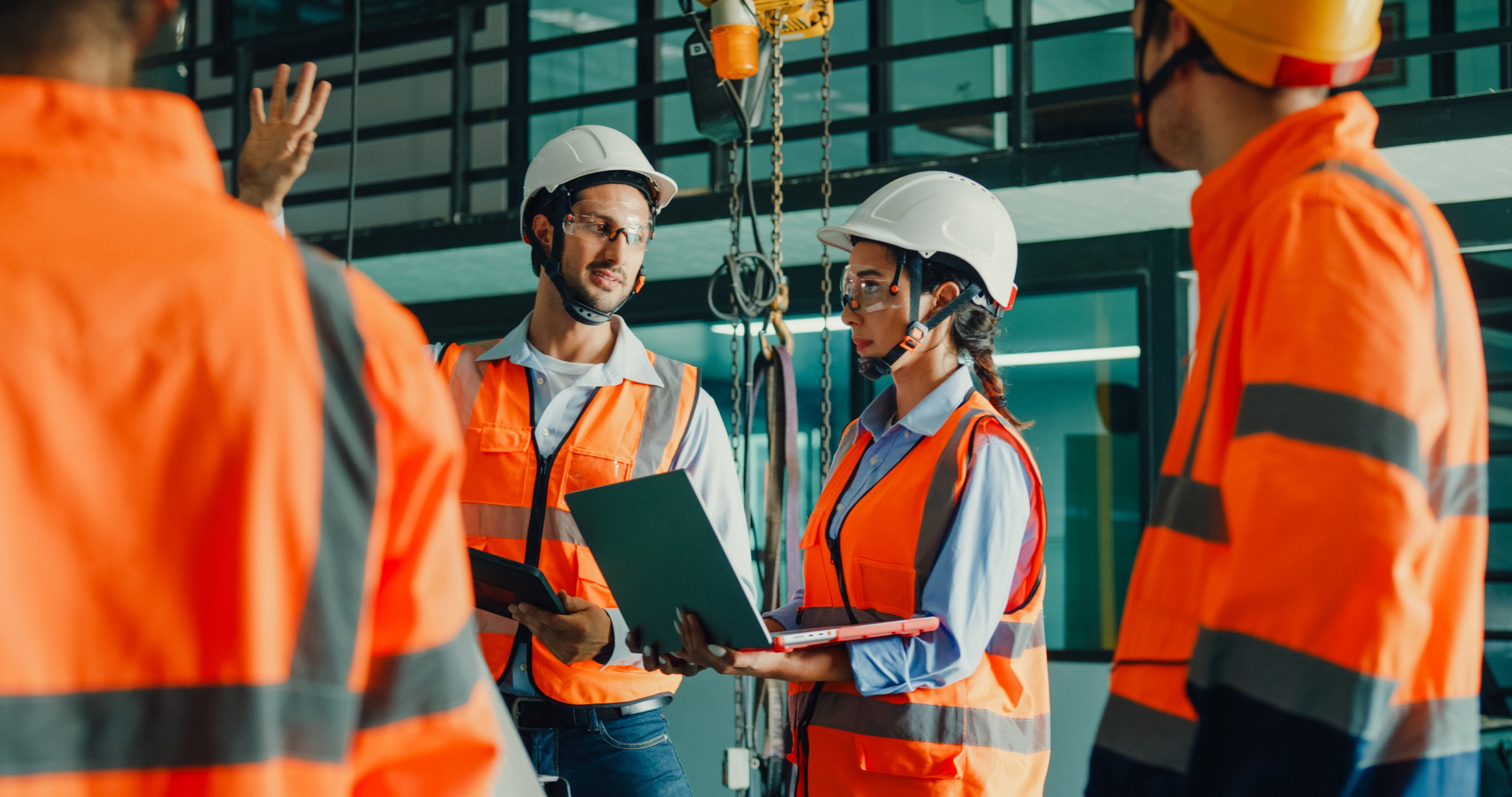 Industrial engineers reviewing plans + laptop in a manufacturing setting
